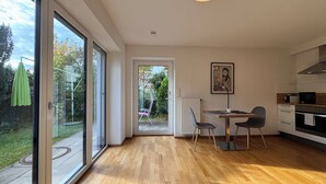 A modern kitchen with a dining area, large windows, and a view of the garden.