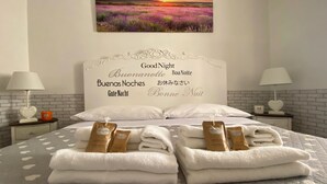 A neatly made bed with white towels and two packages of shampoo and body wash. - Navona "The Corner"  (Roma)