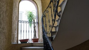 A staircase with a wrought iron railing, a window with a potted plant, and a view of the outside. - Navona "The Corner"  (Roma)