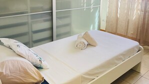 A single bed with a white mattress, a rolled towel, and a decorative pillow. - Central House near the airport (Fiumicino)