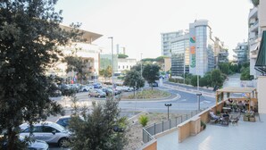 A modern urban street with a café on the right, a roundabout, and buildings with commercial signage. - Central House near the airport (Fiumicino)