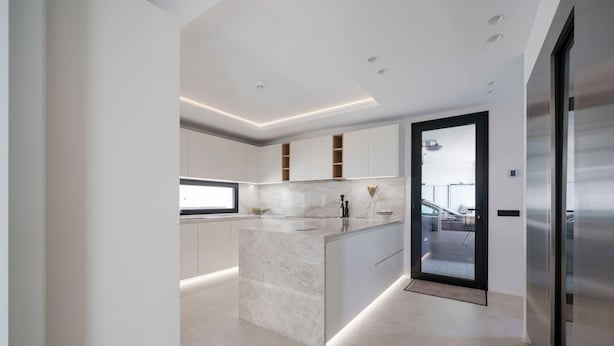 A modern kitchen with a marble island, recessed lighting, and a view to the living area. - Villa la Vista Marbella (Marbella)