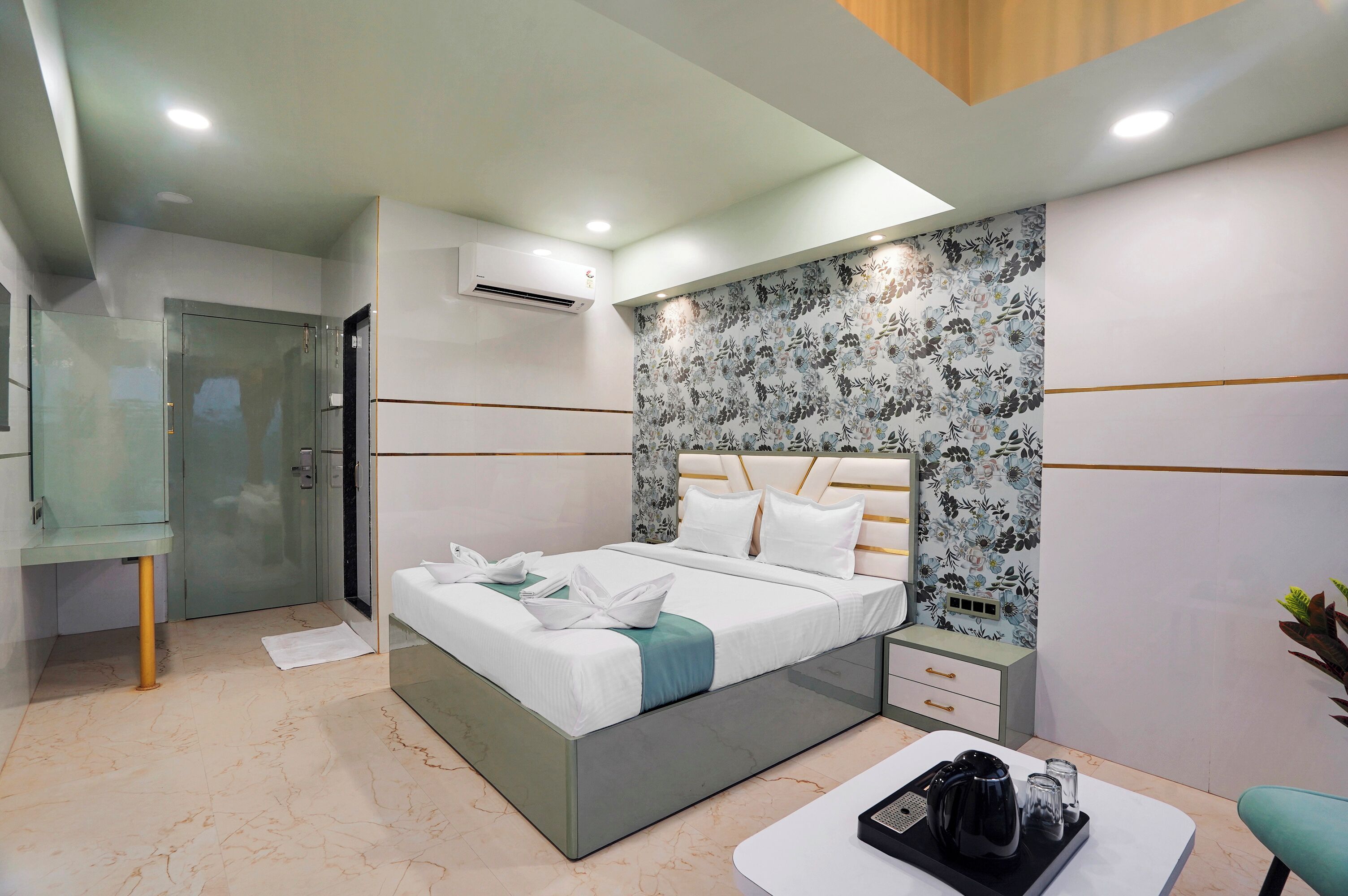 Una habitación de hotel moderna con cama, mesita de noche y un pequeño rincón de estar.