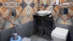 A bathroom with a marble-patterned wall, a sink, a toilet, and a shower.
