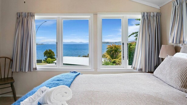 A bedroom with a large bed, a view of the sea, and curtains.