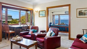A spacious living room with a view of the ocean, a dining area with a table and chairs, and a cozy seating area with leather sofas.