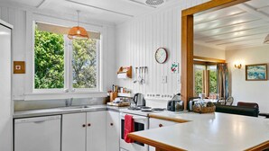 A modern kitchen with white cabinetry, a large island, and a view of greenery outside.