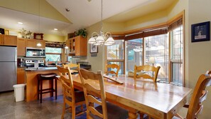 A spacious kitchen with wooden cabinets, a dining table with chairs, and a large window providing a view of the outdoors.