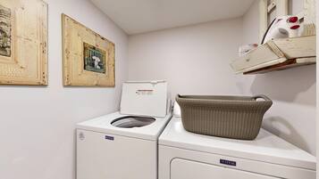 Un espace buanderie équipé d’un lave-linge et d’un sèche-linge Maytag, d’un panier en osier posé sur le sèche-linge et de deux tableaux encadrés accrochés au mur.