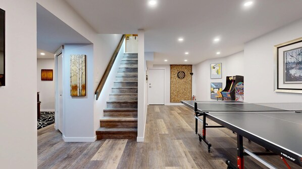 A modern interior with a ping pong table, a staircase, and various wall art.