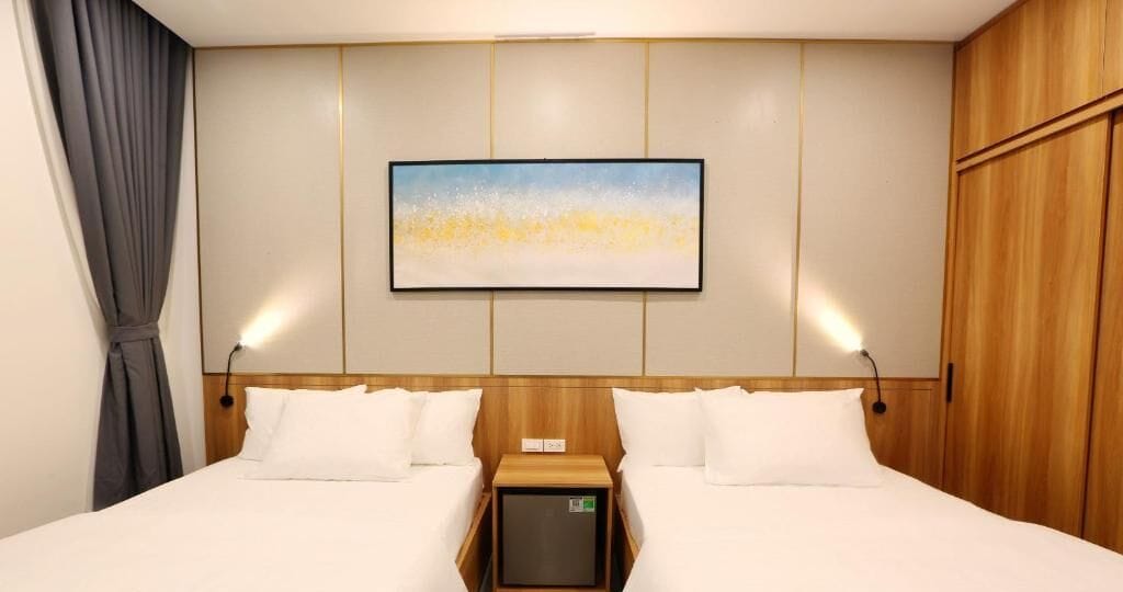 Une chambre d’hôtel avec deux lits, une tête de lit en bois, une table de chevet et un tableau au mur.