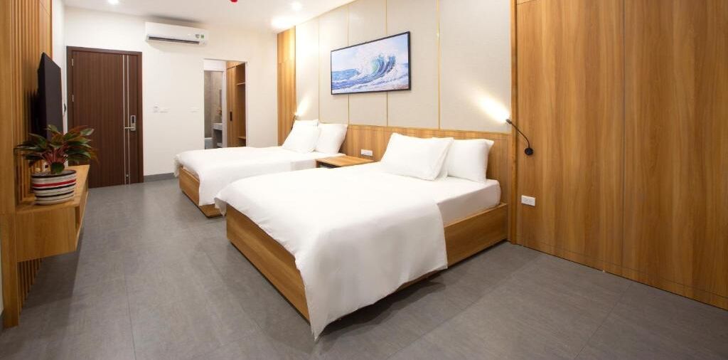 Une chambre d’hôtel avec deux lits, des lambris en bois, un tableau au mur et une plante en pot.