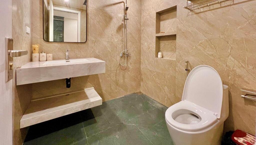 A bathroom with a toilet, a sink, a mirror, and a shower.