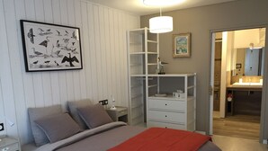 A bedroom with a bed, a bedside table, a nightstand, a white shelving unit, and a framed picture on the wall. - Gîte PMR Balade Océane Lodonnec (Loctudy)