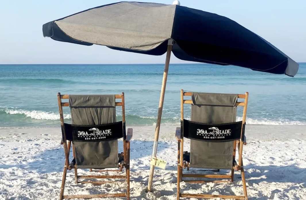 Two beach chairs with a beach umbrella on a sandy beach.