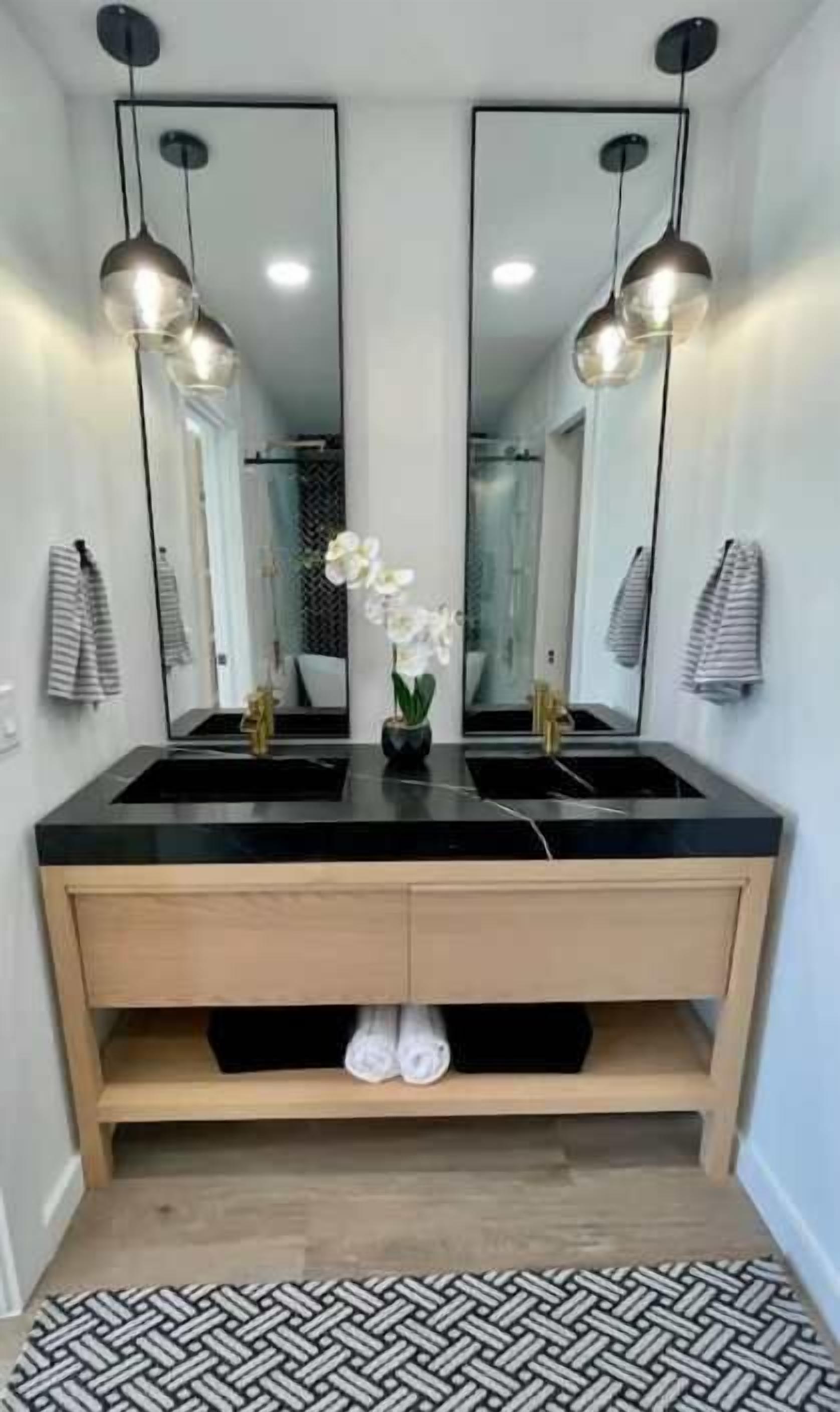 Un baño con dos lavamanos, un espejo, luces colgantes y un perchero para toallas.