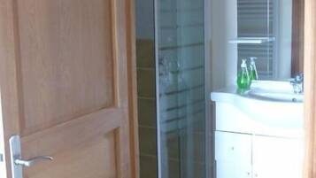 Un baño con cabina de ducha de vidrio, un lavabo blanco y un espejo.