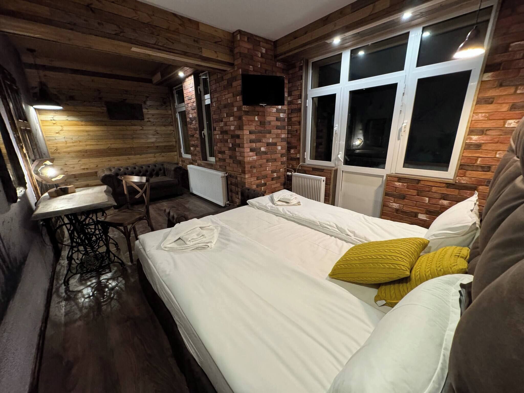 A cozy room with a bed, a table, and a sofa.
