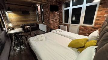 A cozy room with a bed, a table, and a sofa.