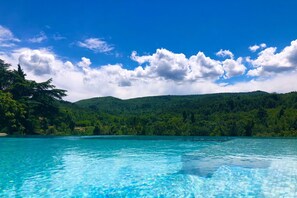 Une piscine d’un bleu éclatant, entourée d’une végétation luxuriante et de collines.