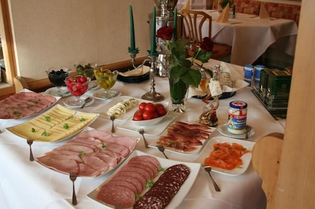 A table with various food items, including meats, cheeses, and fruits, arranged on a white tablecloth.. Hotel Shawi