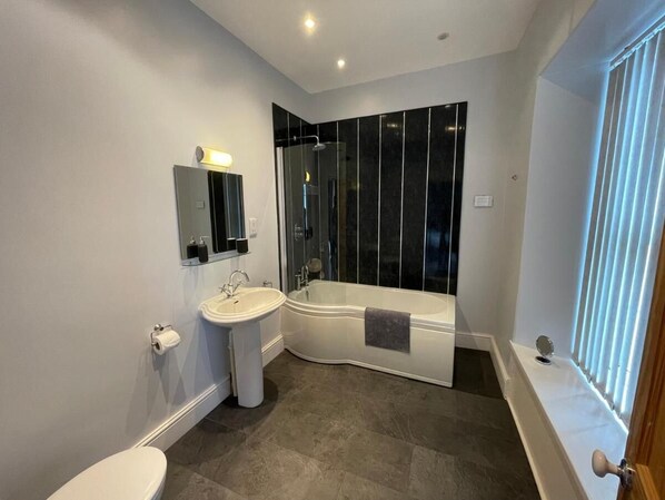 A modern bathroom with a toilet, sink, and bathtub. - The Brookfield Guest House (Braunton)