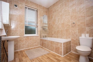 Un baño con lavamanos, inodoro, ducha y ventana.