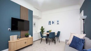 Un salon avec un téléviseur, une table à manger avec des chaises, un canapé et un meuble.