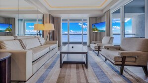 Ein modernes Hotelzimmer mit großem Fenster und Meerblick, einer Couch, einem Couchtisch und einem Fernseher.
