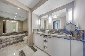 Een moderne badkamer met een ruime wastafel, twee wasbakken, een badkuip en een inloopdouche.