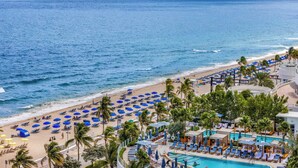 Ein Strandresort mit Poolbereich, Strandstühlen und Palmen.