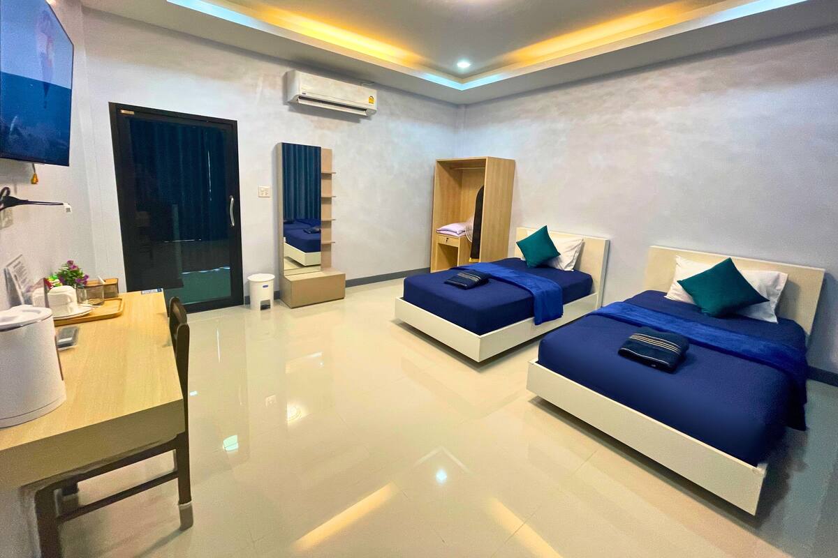 Une chambre d’hôtel moderne équipée de deux lits, d’un bureau, d’une chaise, d’une armoire et d’un appareil de climatisation.