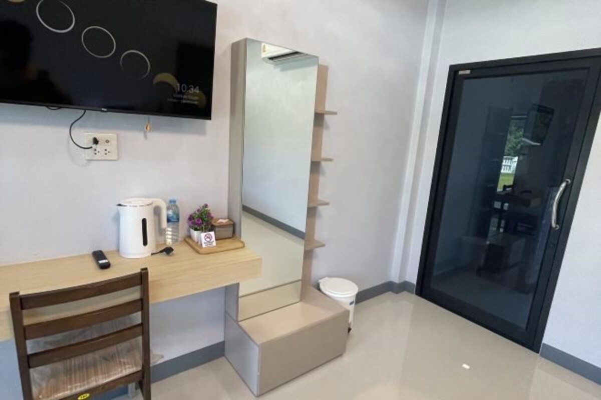 A modern room with a wooden desk, a white kettle, a small plant, and a mirror.