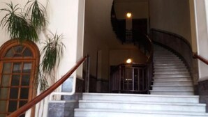 Eine Marmortreppe mit hölzernen Geländern, die zu einer Empore führt.