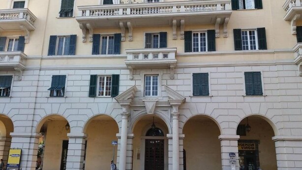 Ein Gebäude mit einer klassischen Fassade, das gewölbte Durchgänge und einen zentralen Eingang zeigt.