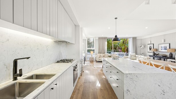 Een moderne keuken met witte kastjes, een marmeren aanrechtblad en een centraal eiland.