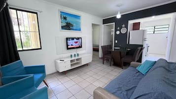Ein kompakter Wohnbereich mit Bett, Fernseher, Essbereich und Küchenzeile.