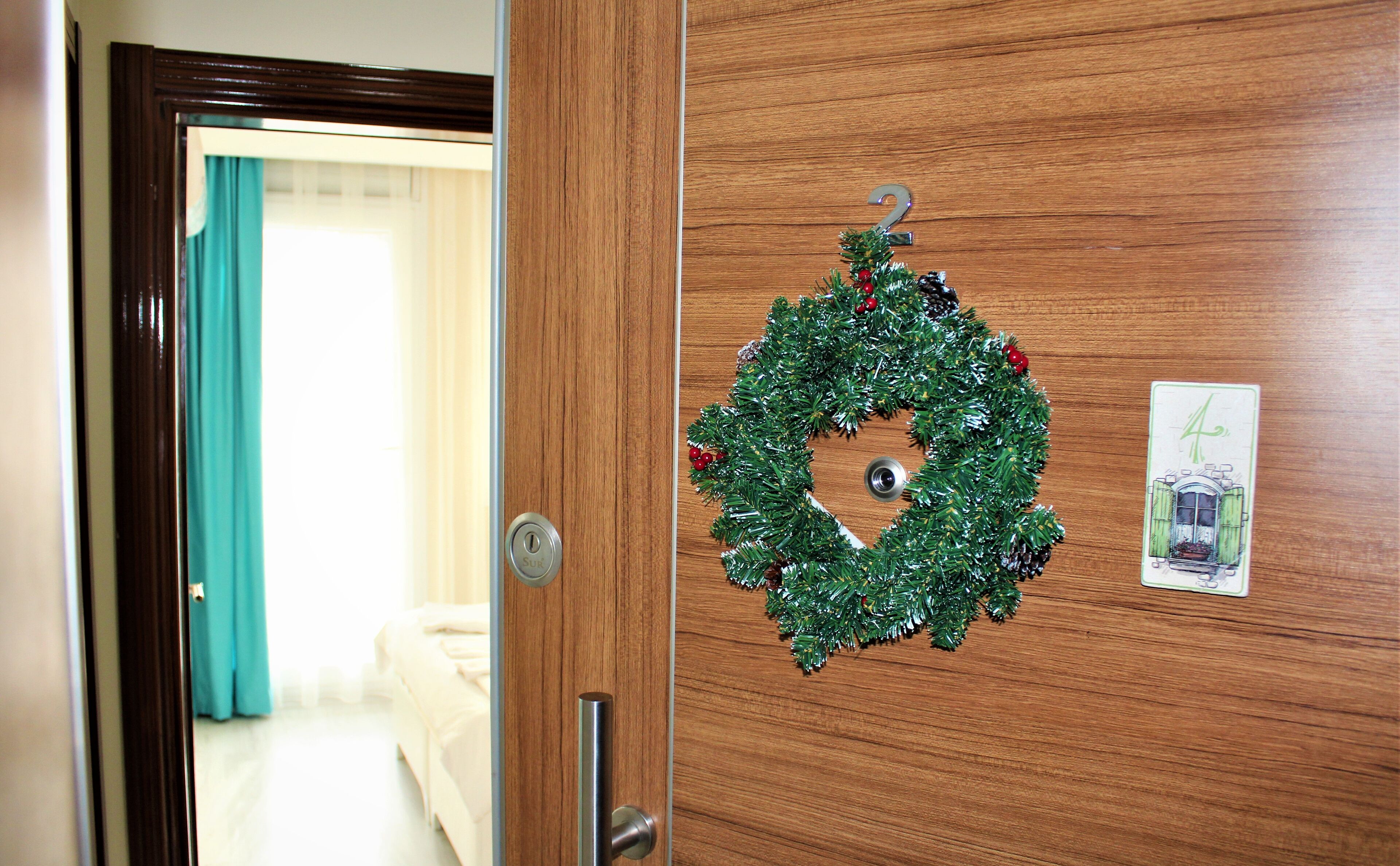 Une porte en bois ornée d’une couronne de Noël et dotée d’un trou de serrure.