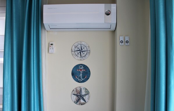 A wall-mounted air conditioner with a remote control, two wall-mounted thermostats, and three nautical-themed wall stickers. - Mavi Restaurant & Apartments 1 (Didim)