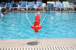 Ein Poolbereich mit Liegestühlen und einem Getränk im Glas.