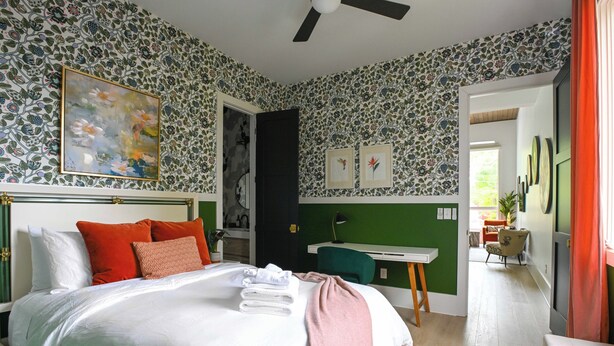 A bedroom with a bed, pillows, a desk, and a chair.