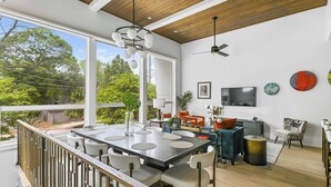 A modern dining area with a large table, chairs, and a view of greenery outside. - Chic 3BR | Rooftop Views | Close to Beltline (Atlanta)