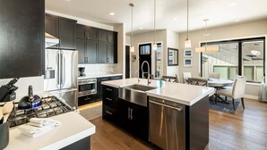 A modern kitchen with stainless steel appliances, a central island, and a dining area with a view.