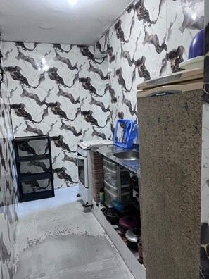 Uma cozinha compacta com painel de fundo de mármore, pia embutida e pequena geladeira.