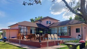 A two-story house with a covered patio area, a swimming pool, and a lawn. - 7Zee View (Nakhon Nayok)
