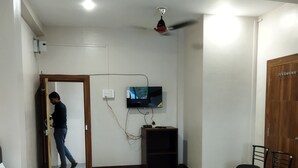 A hotel room with a bed, a television mounted on the wall, a ceiling fan, and a wooden wardrobe. - SR HOTEL KILERAMA ASHTA  (Ashta)