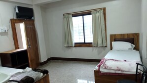 A room with a bed, a wooden cabinet, a television, a window with curtains, and a tiled floor. - SR HOTEL KILERAMA ASHTA  (Ashta)