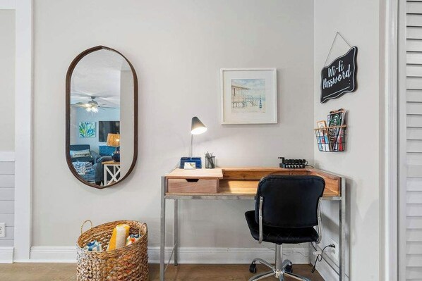 A home office with a desk, chair, and a large mirror.