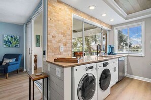 A laundry room with a large mirror, two washing machines, and a countertop.