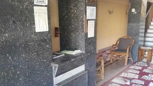 Un espace d’accueil avec un comptoir en marbre, un panneau indiquant qu’il est interdit de fumer et une chaise.